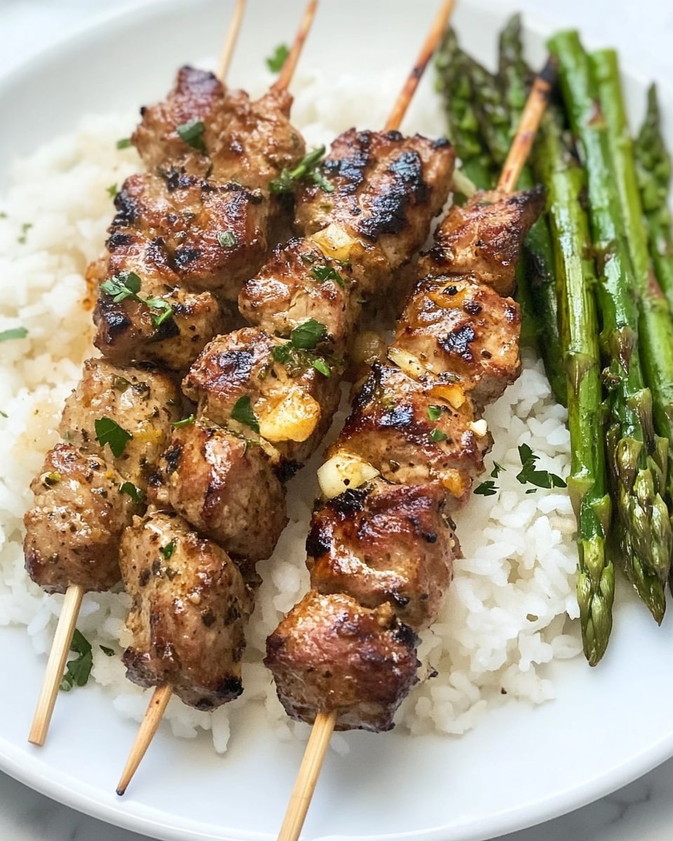 Two grilled skewers of golden-brown meat with visible herbs and small bits of seasoning rest on a bed of white rice on a white plate. The meat appears juicy with slightly charred edges and a textured surface showing pieces of garlic and greenery. To the side of the rice and skewers, there is a neat bundle of vibrant green roasted asparagus spears with a slight shine, indicating light oil or seasoning. The plate sits on a white marbled surface. photo taken with an iphone --ar 4:5 --v 6.1