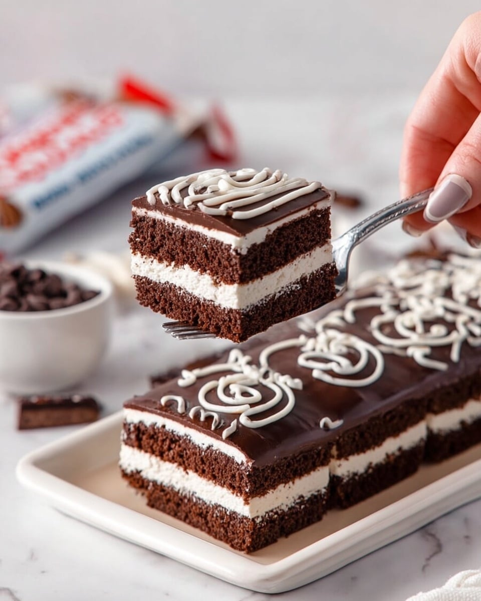 The image shows a square chocolate cake with three visible layers: a thick bottom layer of dark brown chocolate cake, a middle layer of white creamy filling, and a top layer of the same dark brown chocolate cake. The top is covered with a smooth, shiny dark brown chocolate glaze decorated with white icing swirls in a wavy pattern across the surface. One piece of the cake is slightly pulled out to the left, revealing the soft texture of the cake and cream inside. The cake is placed on white parchment paper inside a beige tray, set on a white marbled surface. Photo taken with an iphone --ar 4:5 --v 6.1