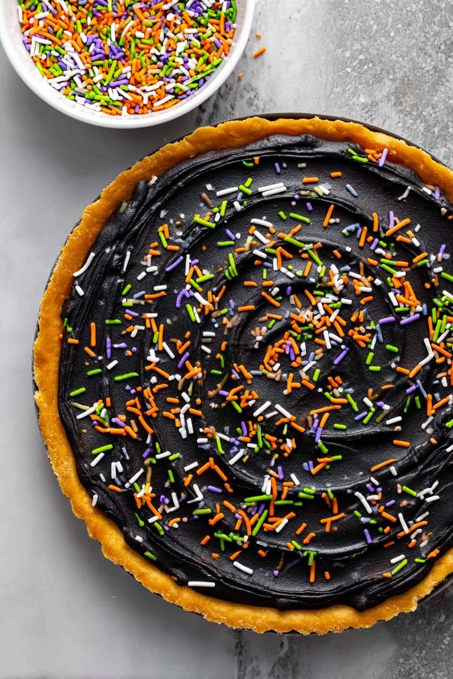 Halloween Pumpkin Spice Cookie Cake, pumpkin spice cookie cake, festive Halloween cookie dessert, fall cookie cake with frosting, spooky pumpkin dessert - A round tart with a golden-brown crust forms the base layer, topped with a thick, smooth layer of black frosting spread evenly across the surface with visible swirl textures. Colorful sprinkles in green, orange, white, and purple are scattered evenly over the black frosting, adding bright pops of color. A white bowl filled with the same sprinkles is placed above the tart on a white marbled surface, visible in the top right corner of the image. photo taken with an iphone --ar 2:3 --v 7