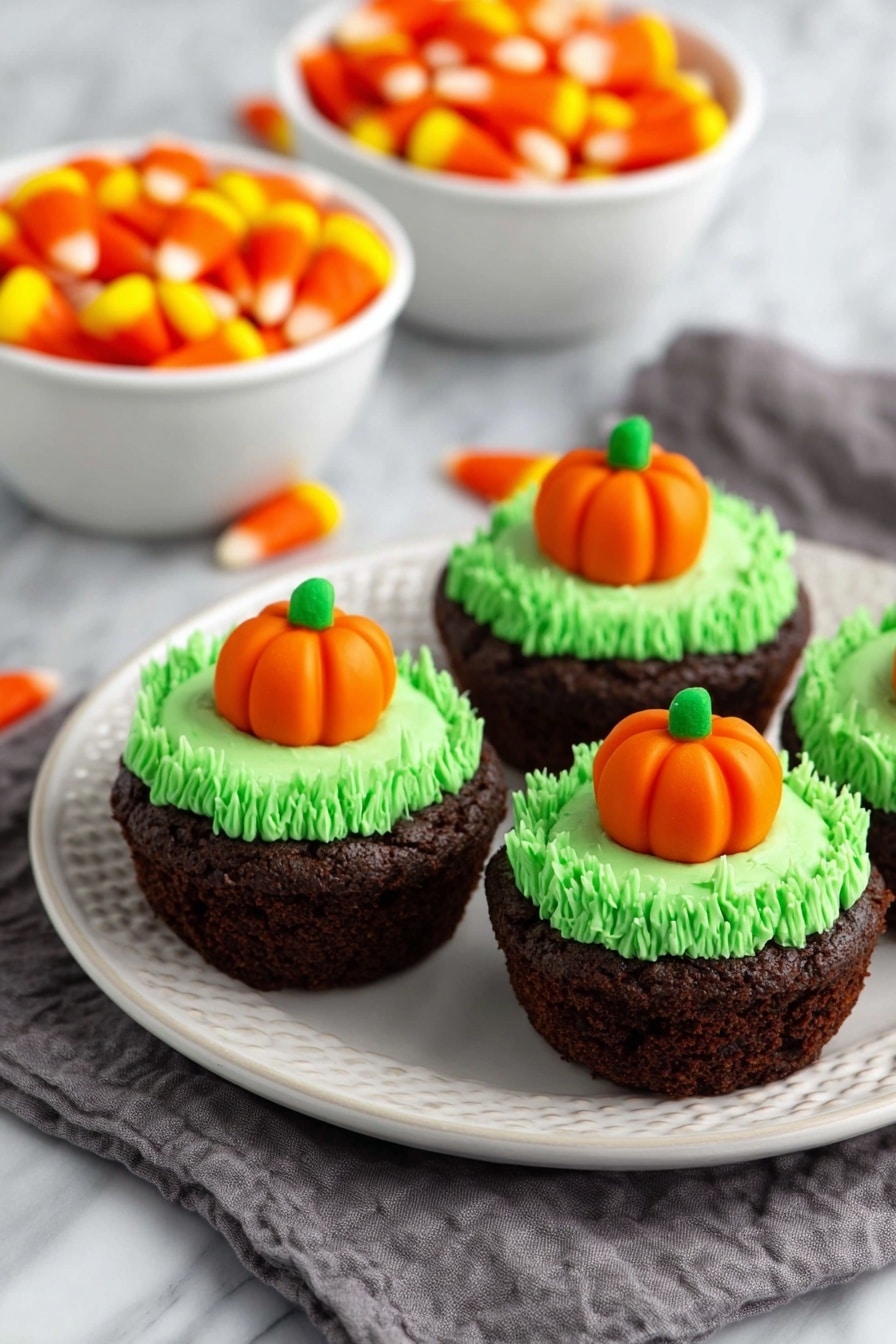 Pumpkin Patch Brownie Bites, fall treats, bite-sized dessert, Halloween party snacks, pumpkin dessert ideas - The image shows a close-up of a rich, dark brown brownie cupcake on a white plate with a white marbled background. The cupcake has one layer of dense, moist chocolate cake with a slightly rough texture. On top is a thick swirl of bright green frosting, piped in tight loops to form a textured ring around the center. In the center of the frosting sits a small, smooth orange pumpkin-shaped candy with green leaves on top, adding a pop of color and detail. Photo taken with an iphone --ar 2:3 --v 7