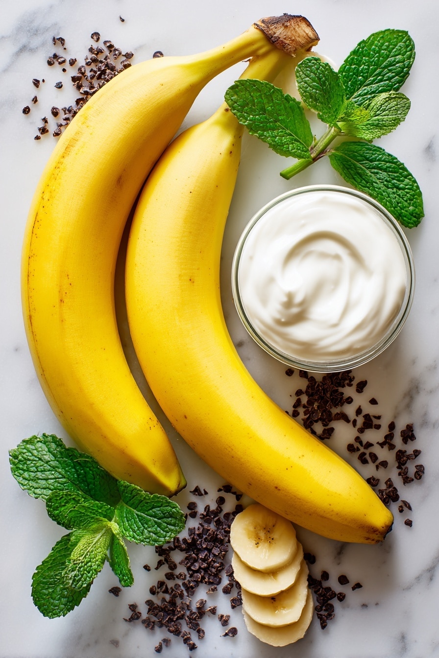 Boonanas – A Frozen Banana Ghost Halloween Treat, Halloween ghost snacks, healthy Halloween treats, fun kid-friendly Halloween desserts, frozen banana ghosts - Flat lay of two large ripe bananas with bright yellow skin, a small glass of smooth white vanilla yogurt, and scattered tiny dark mini chocolate chips with a glossy finish, all naturally arranged with a few banana slices showing their creamy texture, some fresh green mint leaves adding a pop of color, placed on white marbled surface, photo taken with an iphone --ar 2:3 --v 7