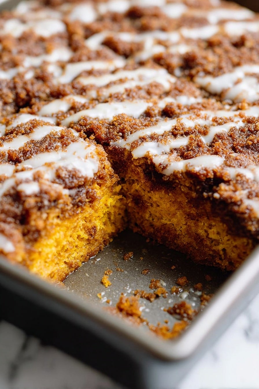 Pumpkin Coffee Cake with Streusel Topping and Optional Glaze, cozy pumpkin coffee cake recipe, easy autumn coffee cake with pumpkin, fall dessert with streusel topping, moist pumpkin spice cake - A close-up view of a rectangular metal baking pan filled with a baked dish divided into nine square pieces. The top layer is a golden brown crust with a rough, crumbly texture and slight darker spots, suggesting a crispy surface. Beneath the crust, there are hints of a soft, orange layer peeking through in a few spots, showing a moist filling. The pan is placed on a wire rack with a dark surface underneath, creating a rustic feel. photo taken with an iphone --ar 2:3 --v 7