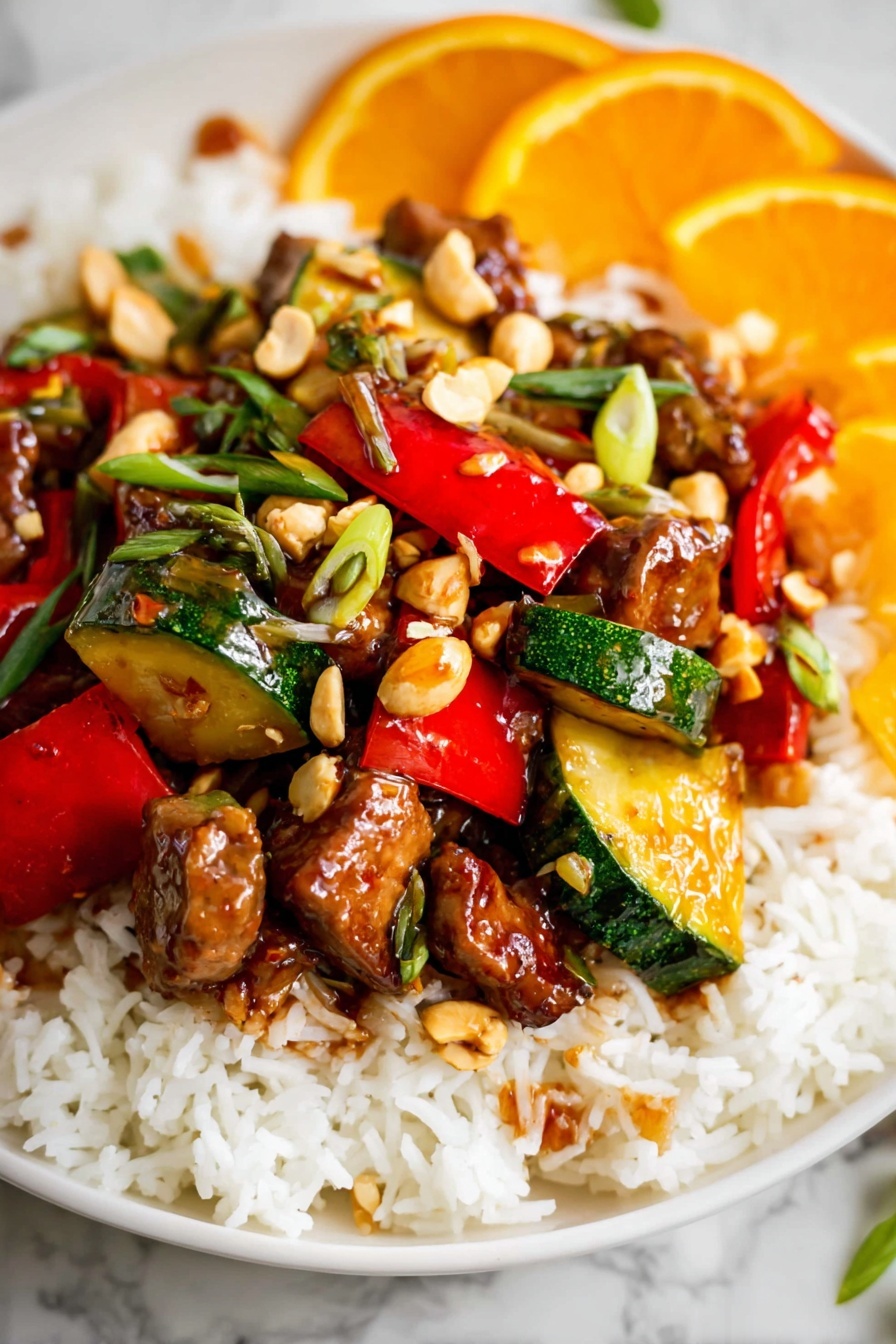 Kung Pao Chicken with Orange Chili Sauce and Crispy Vegetables, spicy chicken stir fry with citrus, quick Asian chicken recipe, flavorful crispy vegetable dishes, easy Chinese chicken dinner - The dish is served on a white plate with a base layer of fluffy white rice spread evenly. On top of the rice, there is a colorful mix of stir-fried vegetables and meat pieces. The vegetables include vibrant red bell peppers and green zucchini chunks, both cut into bite-sized pieces with a glossy, cooked texture. Scattered throughout are small chunks of browned meat coated in a shiny, slightly sticky sauce. There are also whole light brown peanuts and thinly sliced green herbs sprinkled on top, adding some texture and color contrast. In the background, there are slices of bright orange fruit, adding a fresh, citrusy touch. The whole presentation sits on a white marbled surface. photo taken with an iphone --ar 2:3 --v 7