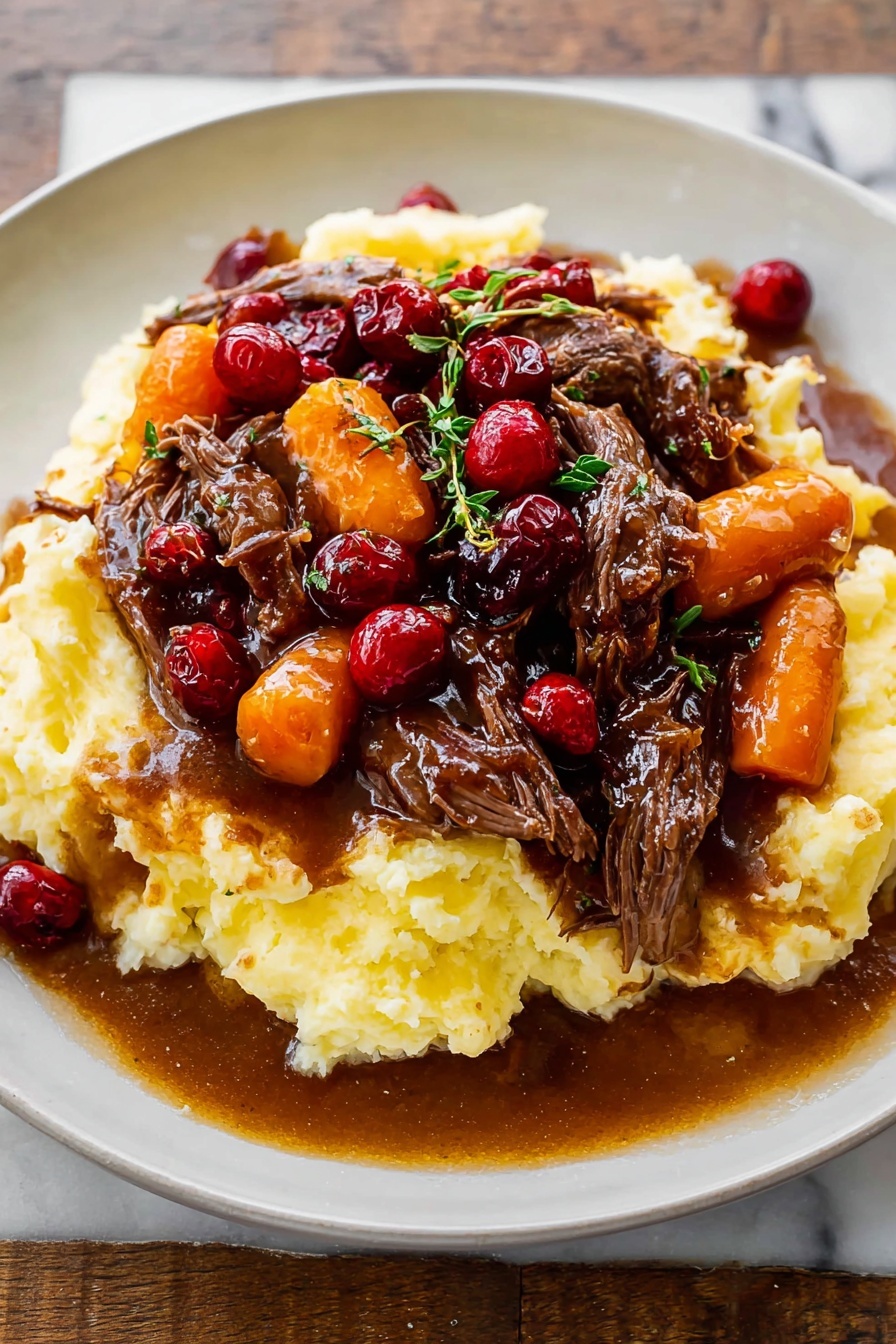 Cranberry Balsamic Roast Beef, cranberry balsamic sauce, slow roast beef recipes, holiday beef main dish, savory beef dinner ideas - A white plate holds a dish with three main layers: the base is a thick, creamy mashed potato layer, pale yellow and textured with soft peaks; on top of that sits a rich brown gravy mixed with tender, shredded dark brown beef pieces; the top layer features bright orange carrot slices and glossy red cranberries scattered throughout, with small green herb sprigs for garnish. The gravy looks shiny and slightly thick, pooling a little on the plate around the mashed potatoes. The whole plate is on a white marbled surface. photo taken with an iphone --ar 2:3 --v 7