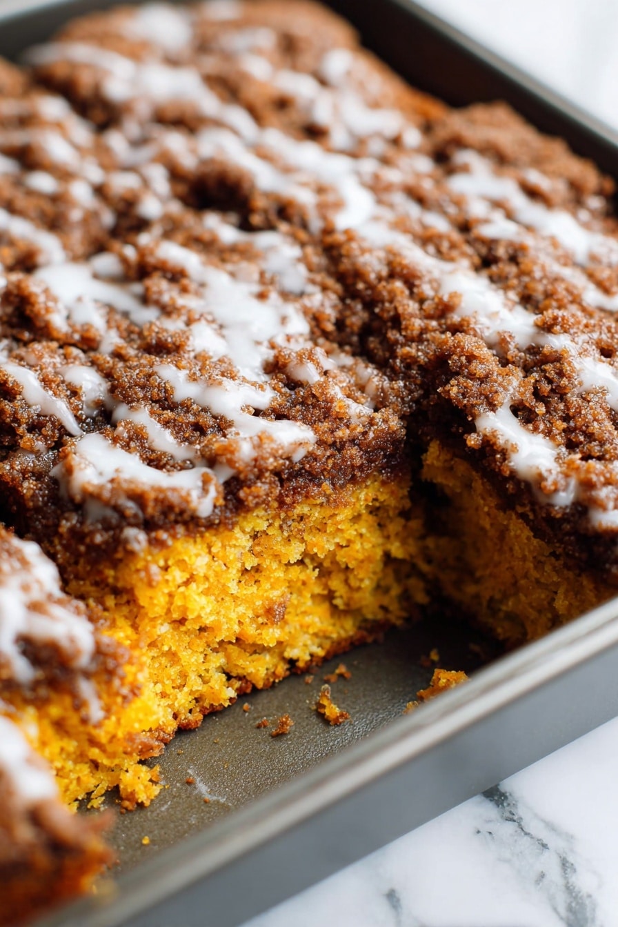 Pumpkin Coffee Cake with Streusel Topping and Optional Glaze, cozy pumpkin coffee cake recipe, easy autumn coffee cake with pumpkin, fall dessert with streusel topping, moist pumpkin spice cake - A close-up view of a square cake in a baking pan, showing one large piece missing from the corner of the cake. The cake has two visible layers: the bottom layer is bright orange with a moist and soft texture, and the top layer is thick with a dark brown crumbly topping mixed with a white glaze lightly drizzled over it. The baking pan is metallic, and the background surface is a white marbled texture. photo taken with an iphone --ar 2:3 --v 7