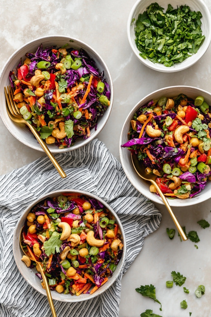 Chopped Thai-Inspired Chickpea Salad with Curry Peanut Dressing, Thai chickpea salad, Thai-inspired vegan salad, healthy chickpea salad, flavorful peanut dressing - Three white bowls filled with a colorful salad sit on a white marbled texture. Each bowl holds a mix of dark purple cabbage pieces, orange shredded carrots, light yellow chickpeas, green sliced scallions, red bell pepper chunks, and fresh green cilantro leaves scattered on top. There are some whole cashews on the salad adding a light beige color. Each bowl has a gold spoon resting inside, and a striped white and navy cloth lies underneath two of the bowls. A small white bowl with chopped cilantro sits above the bowls, with some cilantro leaves scattered on the surface. photo taken with an iphone --ar 2:3 --v 7