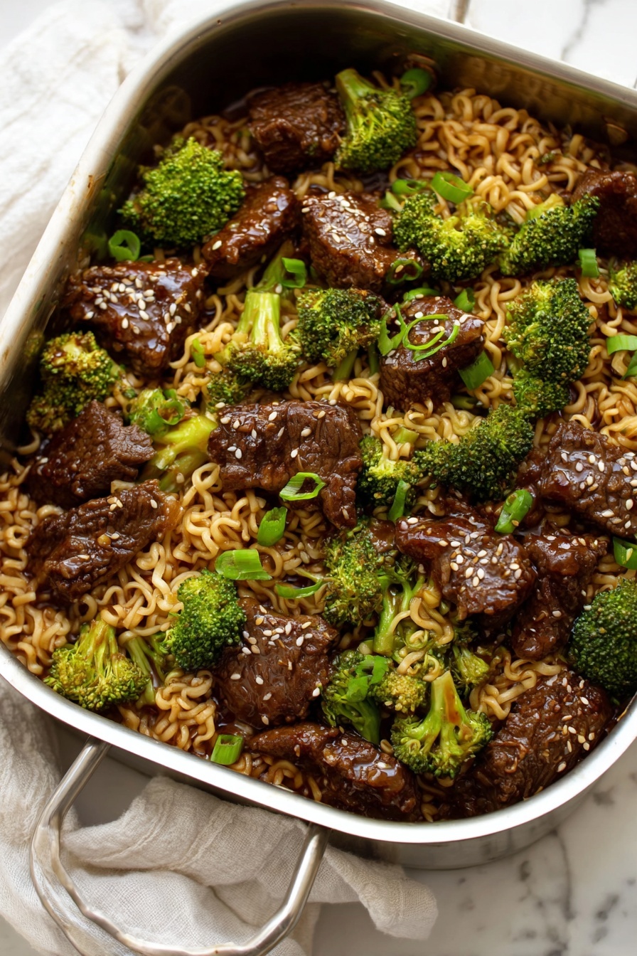 Beef Broccoli Ramen Stir Fry, quick beef broccoli stir fry, easy ramen noodle stir fry, healthy beef stir fry recipes, savory Asian stir fry - A metal pan filled with a mixture of three main layers: the first layer is curly light brown noodles that look soft and slippery, the second layer is bright green broccoli florets spread evenly, and the third layer is dark brown pieces of cooked beef scattered throughout. The beef pieces have a shiny glaze on them and some white sesame seeds sprinkled on top. Small pieces of chopped green onion add small bright green spots among the noodles and beef, all resting on a white marbled surface with a white cloth in the background. photo taken with an iphone --ar 2:3 --v 7