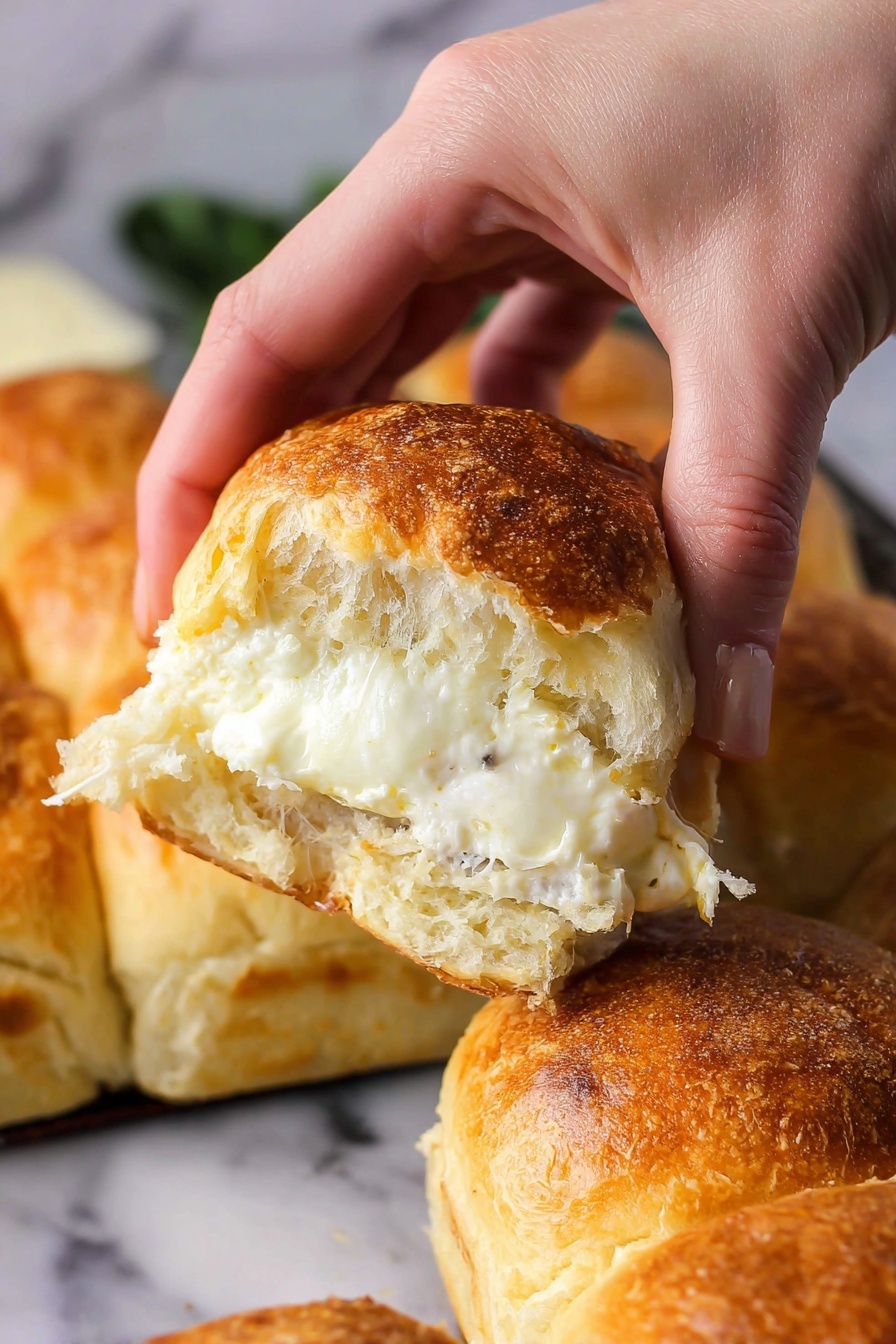 Cheesy Garlic Butter Pull Apart Rolls, cheesy garlic bread, pull apart bread recipe, cheesy bread rolls, garlic butter bread - A woman's hand is pulling apart a soft bread roll that is golden brown on top with a slightly crispy crust. Inside, there is one thick, melted white cheese layer with a creamy texture visible in the center. The background shows more bread rolls that are golden on top, all placed on a white marbled surface. The photo taken with an iphone --ar 2:3 --v 7