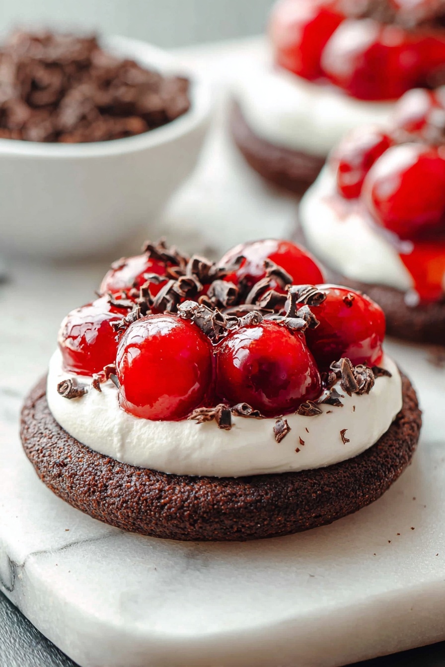 Chocolate Cherry Cheesecake Cookies, cherry cheesecake cookie recipe, chocolate cherry dessert cookies, easy cheesecake cookie, chocolaty cherry cookies - The image shows a dessert with three layers on a white marbled surface. The bottom layer is a thick, round dark brown chocolate cookie with a coarse texture. The middle layer is a white creamy topping, spread evenly in a smooth circle covering the cookie’s surface. On top, there is a shiny bright red cherry topping that looks wet and glossy, with whole cherries visible. Small dark brown curled chocolate pieces are sprinkled over the cherry topping and creamy layer, adding texture and contrast. In the background, a white bowl filled with more dark brown chocolate curls is blurred, along with a second dessert of the same kind slightly out of focus. photo taken with an iphone --ar 2:3 --v 7
