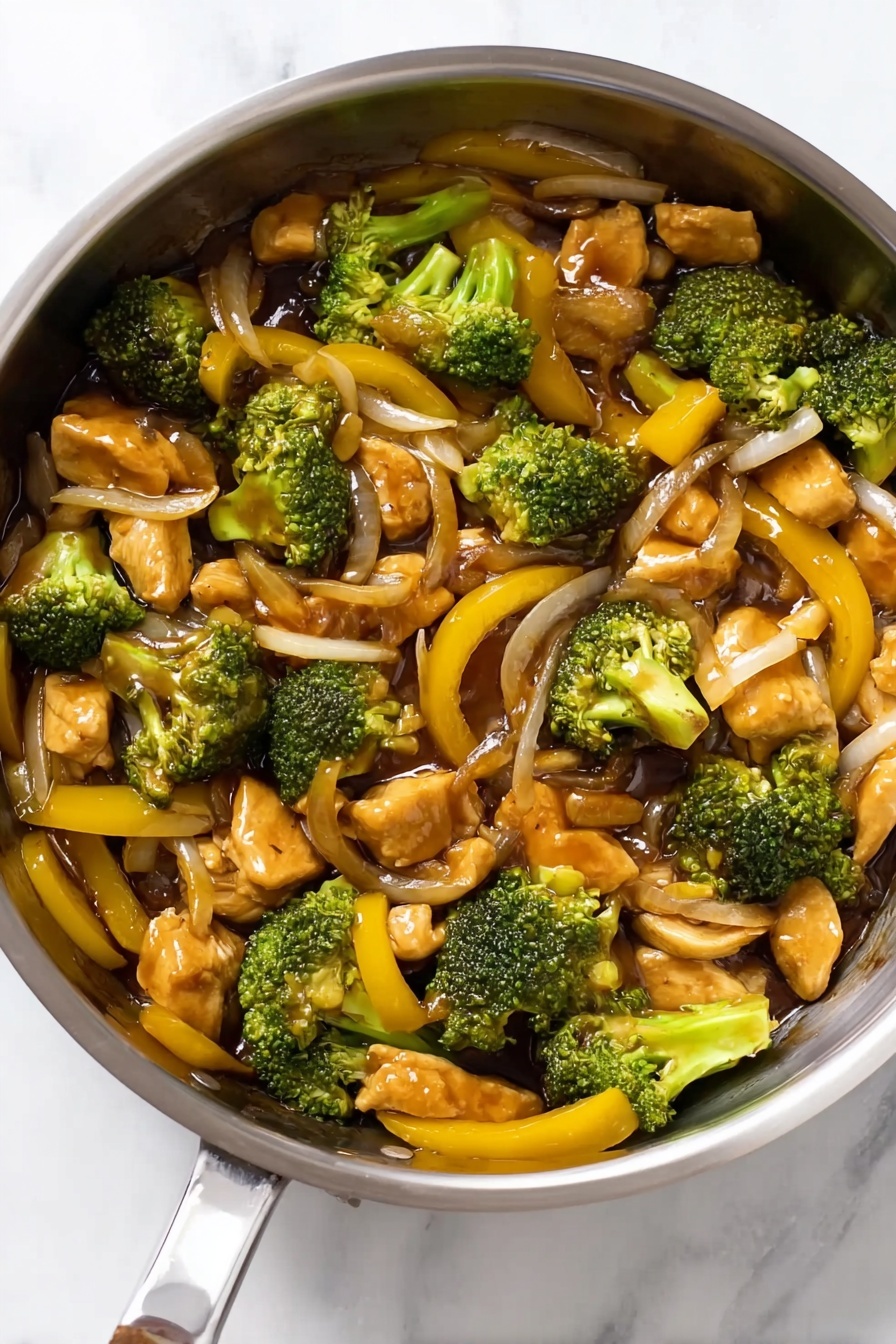Quick Chicken Broccoli Stir Fry, healthy stir fry recipes, easy weeknight dinner, fast chicken stir fry, delicious broccoli chicken dish - The image shows a shiny stainless steel pan filled with a colorful stir-fry dish. The dish has several layers of ingredients: bright green broccoli pieces with a rough texture, soft-looking chunks of light brown chicken, thin yellow bell pepper strips with a smooth surface, and slices of translucent onion. The ingredients are mixed evenly, with a glossy brown sauce coating them, giving a slightly wet and shiny look. The pan is placed on a surface with a white marbled texture. photo taken with an iphone --ar 2:3 --v 7