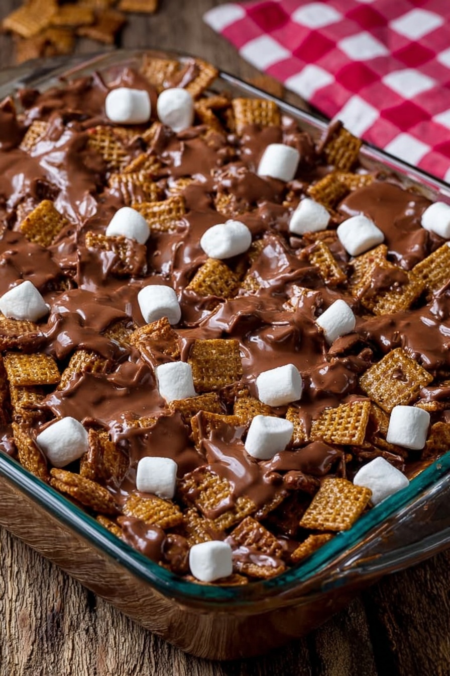 Golden Grahams S'Mores Bars, s'mores bars with Golden Grahams, easy s'mores bar recipe, no-bake s'mores bars, marshmallow chocolate cereal bars - The image shows a clear glass baking dish filled with a mix of square cereal pieces covered in melted milk chocolate, creating a shiny, smooth brown layer that coats the cereal unevenly. Scattered throughout the top are small, white marshmallows that stand out against the chocolate and cereal mix. The dish is placed on a rough wooden surface with a blurred red and white checkered cloth in the background. Photo taken with an iphone --ar 2:3 --v 7