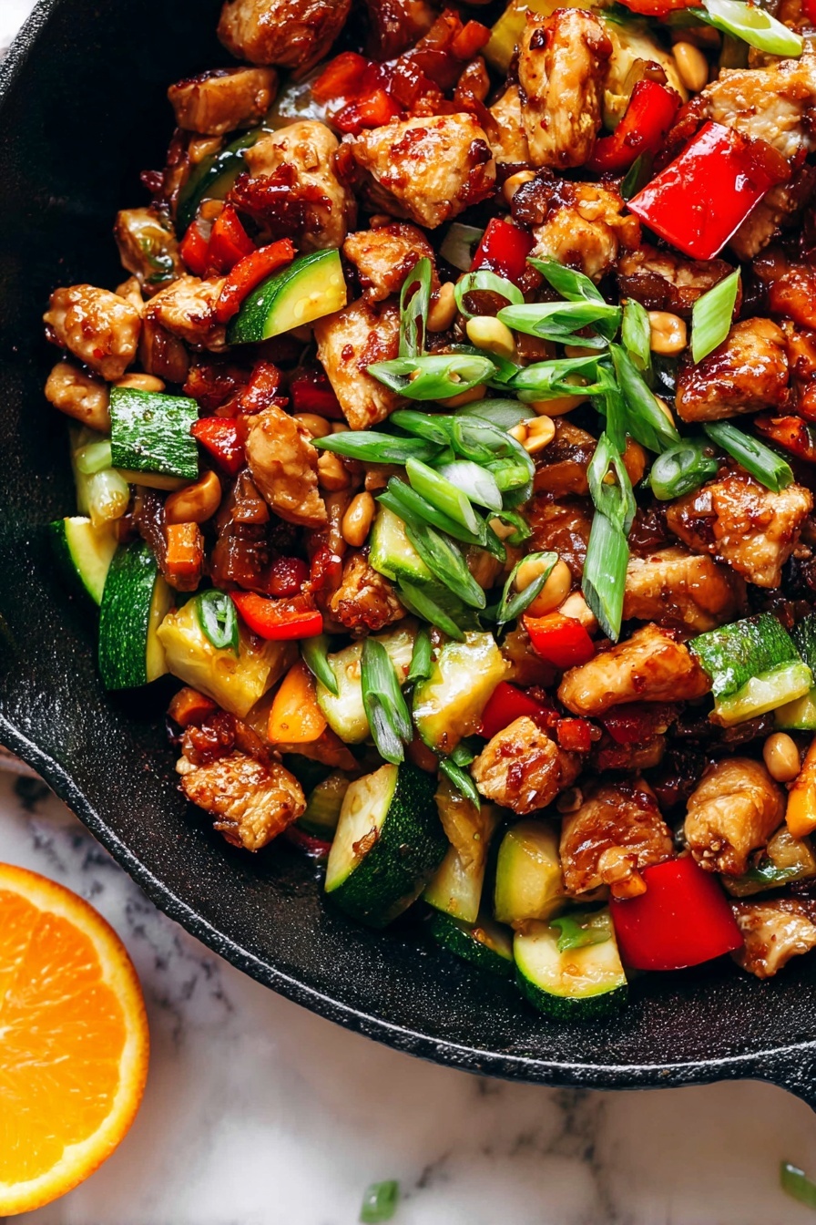 Kung Pao Chicken with Orange Chili Sauce and Crispy Vegetables, spicy chicken stir fry with citrus, quick Asian chicken recipe, flavorful crispy vegetable dishes, easy Chinese chicken dinner - The image shows a close-up of a black cast iron pan filled with a colorful stir-fry dish that has three main layers. The first layer has browned chicken cubes with a shiny, caramelized texture scattered throughout the pan. The second layer has chopped vegetables, including bright red bell peppers and chunks of green zucchini with a cooked but firm look. The third layer is made up of small, light brown peanuts and thin slices of green onions sprinkled on top, adding a fresh touch. The pan sits on a white marbled surface, and there is a slice of bright orange on the edge of the pan. The light in the photo makes the food look vibrant and appetizing photo taken with an iphone --ar 2:3 --v 7