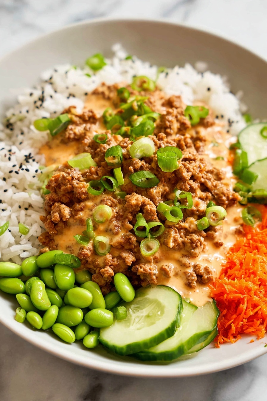 Ground Turkey Rice Bowls with Bang Bang Sauce, easy ground turkey dinner, healthy turkey rice bowls, quick weeknight dinner recipes, flavorful bang bang sauce - A white plate holds a colorful, layered meal starting with a base of white rice scattered with small black seeds. On top of the rice, there is a generous layer of brown ground meat covered in a creamy, light orange sauce. Bright green sliced scallions are sprinkled over the meat and sauce. Around the main layers are small piles of bright green edamame, thin slices of cucumber, and grated orange carrots, all sitting on a white marbled surface. Photo taken with an iphone --ar 2:3 --v 7