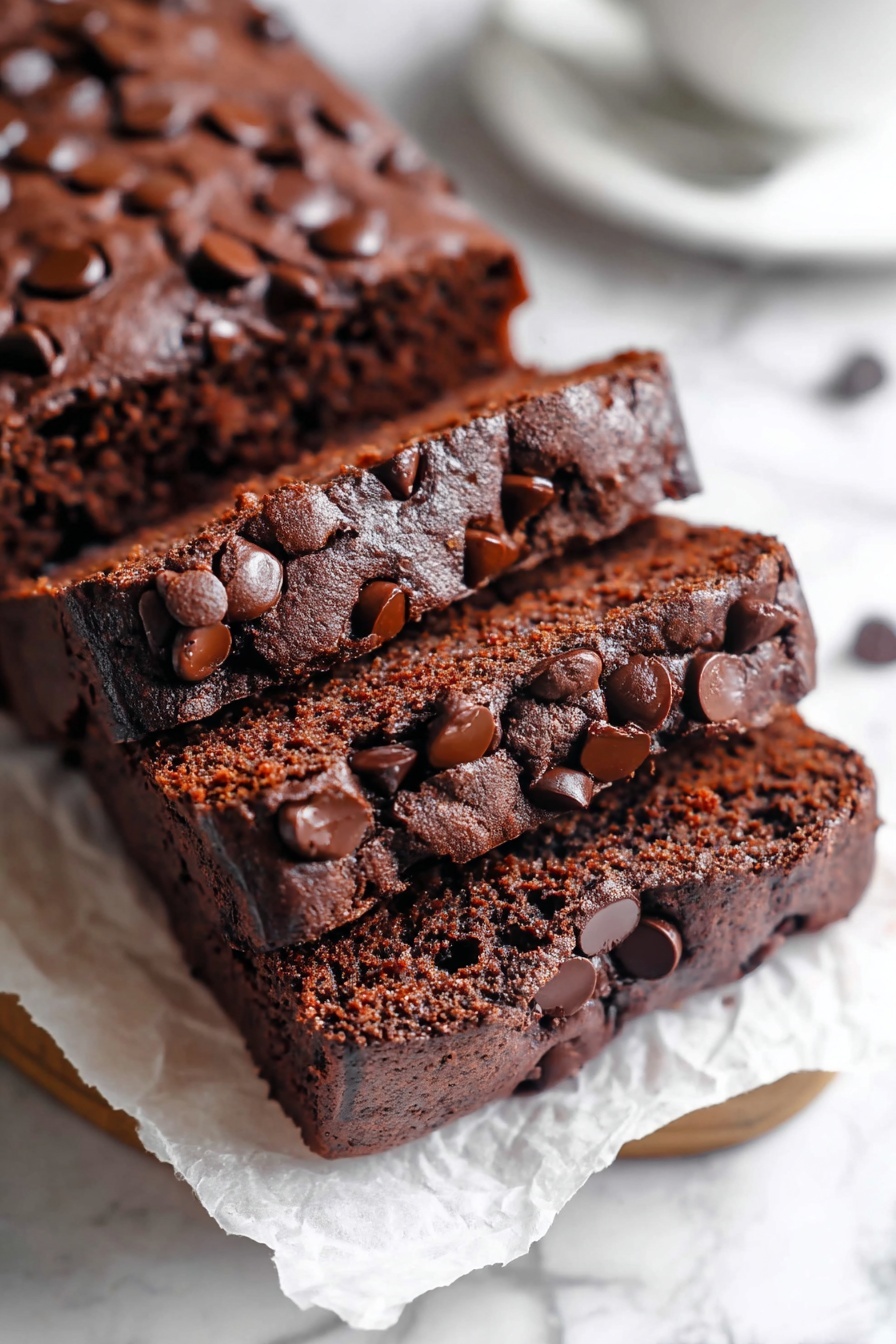Chocolate Brownie Bread, brownie bread recipe, chocolate bread recipe, fudgy bread, easy brownie bread - A stack of five thick, square chocolate brownies arranged diagonally on crinkled white parchment paper over a white marbled surface. Each brownie has a slightly cracked, shiny top layer with scattered dark chocolate chips embedded across the surface. The brownies show a dense, moist, and rich dark brown interior. Photo taken with an iphone --ar 2:3 --v 7