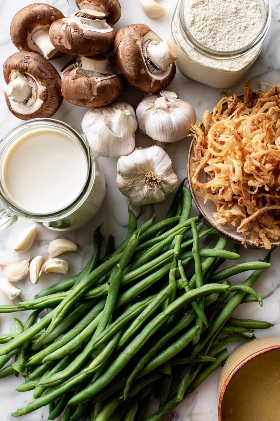 Vegan Green Bean Casserole, vegan green bean casserole without dairy, plant-based green bean casserole, healthy vegan side dish, holiday vegan casserole - Flat lay of fresh green beans with vibrant deep green hues, a cluster of earthy brown sliced mushrooms showing their soft texture, several plump garlic cloves with smooth off-white skin, a small mound of golden crispy french fried onions with a crunchy look, a glass jug of creamy white coconut-almond creamer, a clear container of pale beige raw flour, and a small bowl of rich golden vegetable broth, all naturally arranged with some beans and garlic cloves gently overlapping, placed on white marbled surface, photo taken with an iphone --ar 2:3 --v 7