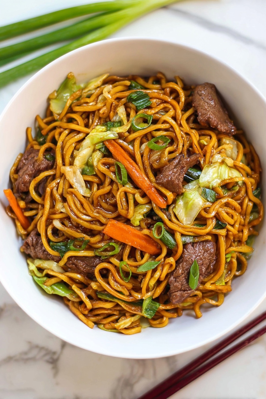 Beef Lo Mein Stir-Fry, quick beef stir-fry recipe, easy Chinese beef and noodle dish, flavorful veggie stir-fry, tender beef lo mein - A white bowl filled with stir-fried noodles piled in the center with a shiny, dark orange color. Mixed throughout the noodles are pieces of cooked dark brown meat, bright orange carrot strips, light green cabbage leaves, and green onions with a fresh texture. The bowl sits on a white marbled surface, with green onions and dark red chopsticks placed nearby. The dish looks warm and saucy with a mix of soft vegetables and tender meat photo taken with an iphone --ar 2:3 --v 7