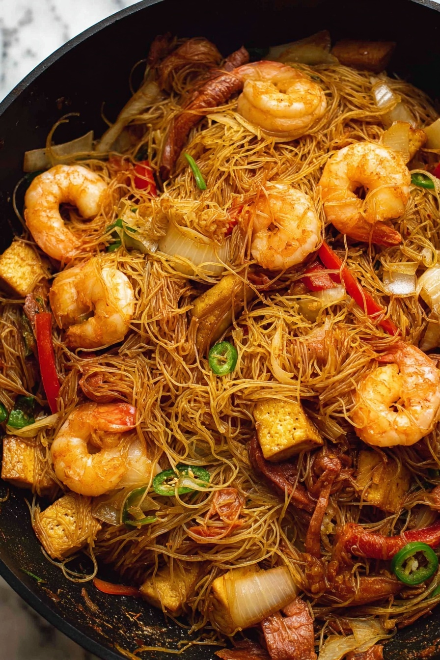 Singapore Noodles with Shrimp and Char Siu, Singapore Noodles, Shrimp and Char Siu Stir-fry, Asian noodle recipes, quick Asian dinner ideas - A black pan filled with stir-fried thin noodles mixed with large cooked shrimp that are a light orange color with a slightly shiny texture. There are pieces of sliced red bell pepper and green chili scattered throughout the noodles, along with chunks of browned tofu that have a slightly crispy outside. Thin slices of cooked brown meat and translucent, soft-looking onion slices are also mixed in. The noodles are tangled and lightly coated in a soy-colored sauce. The background is a white marbled texture. photo taken with an iphone --ar 2:3 --v 7