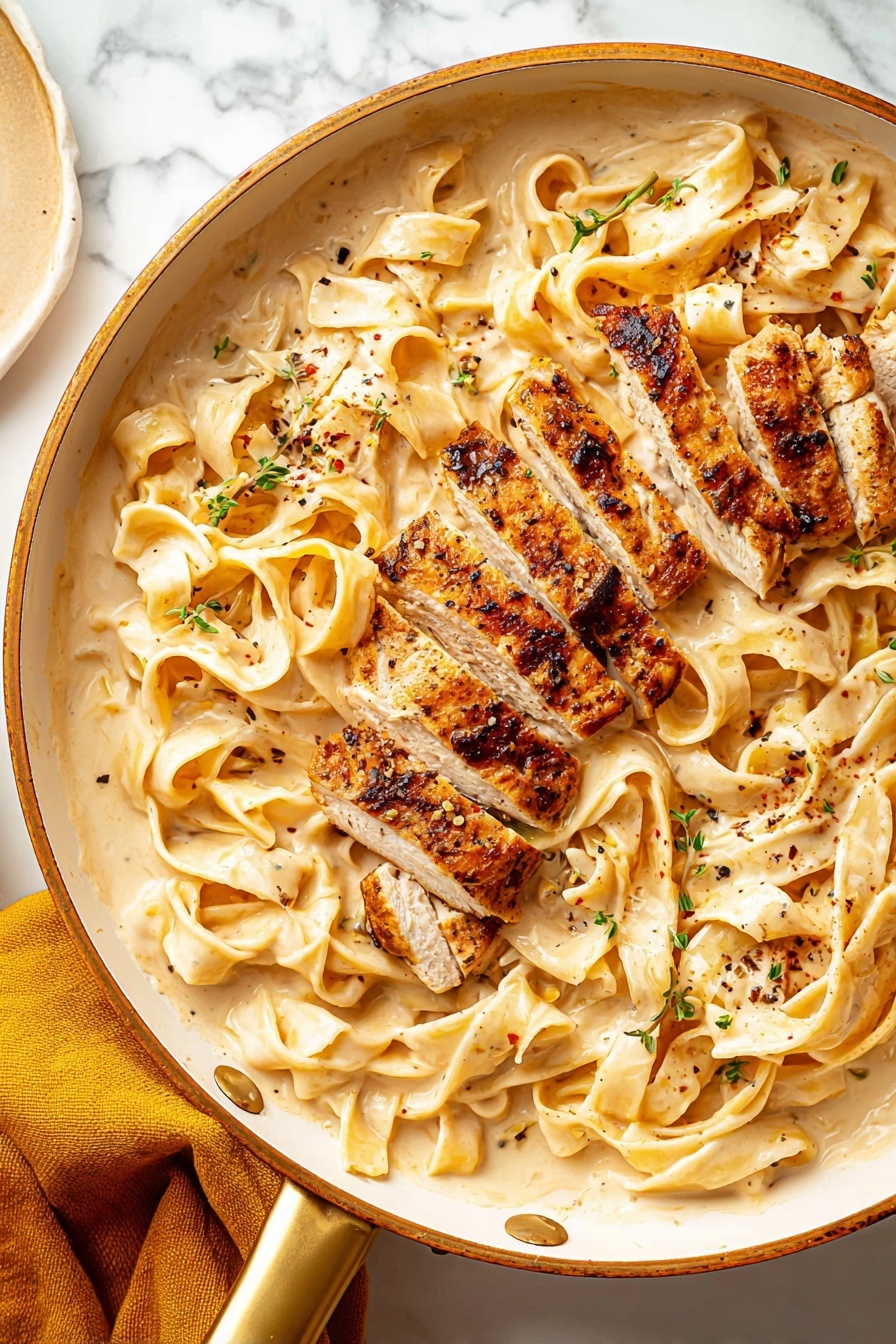 Creamy Fettuccine Alfredo with Chicken, easy chicken Alfredo pasta, homemade Alfredo sauce, comforting chicken pasta dish, quick weeknight Alfredo - This image shows a white pan with a gold handle filled with wide flat noodles in a creamy light beige sauce, spread evenly across the pan as the bottom layer. On top, there are several thick pieces of grilled chicken, cut into strips with a browned, slightly charred crust and tender, light-colored inside. Small green herb bits and black pepper flakes are sprinkled over the noodles and chicken, adding texture and color contrast. The pan is placed on a white marbled surface, with a mustard yellow cloth partially visible on the lower left side. Photo taken with an iphone --ar 2:3 --v 7