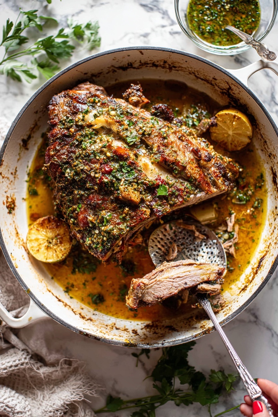 Slow Roasted Lamb Shoulder with Mint Sauce, Lamb shoulder recipe, Roasted lamb dinner, Mint sauce for lamb, Easy lamb roast - A large piece of roasted meat with a brown crispy herb crust on top sits in the center of a white cast iron pot. The meat has visible bone, and the herb crust includes green parsley and spices giving a textured, uneven surface. Underneath the meat, there is a golden-brown juicy sauce with visible slices of lemon and pieces of cooked onions. A metal fork held by a woman's hand is pulling apart a slice of the tender meat, revealing its soft inner texture. To the right inside the pot is a hammered metal spoon resting in the sauce. Around the pot, there are scattered fresh green herbs on a white marbled surface, and a small glass bowl with herb sauce is placed behind the pot. photo taken with an iphone --ar 2:3 --v 7