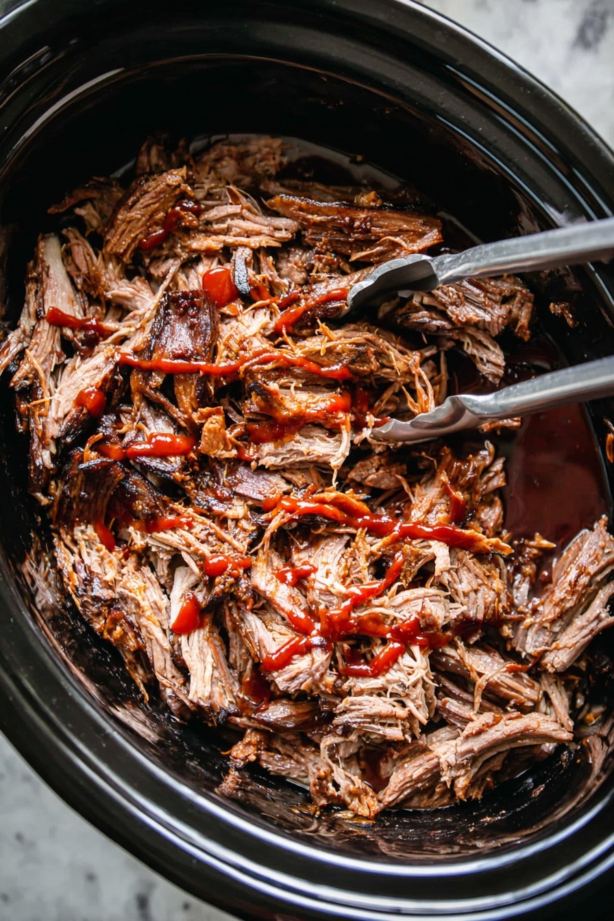 Slow Cooker Pulled Pork, Pulled Pork recipe, tender slow cooker pork, easy pork dinner, homemade pulled pork - A close-up image of shredded cooked meat with dark brown edges and lighter brown inside, placed inside a black slow cooker. The meat is covered with red sauce drizzled unevenly over the top. A silver fork and silver tongs are partially visible inside the slow cooker, placed on the left and right sides of the meat. The slow cooker sits on a white marbled surface. photo taken with an iphone --ar 2:3 --v 7
