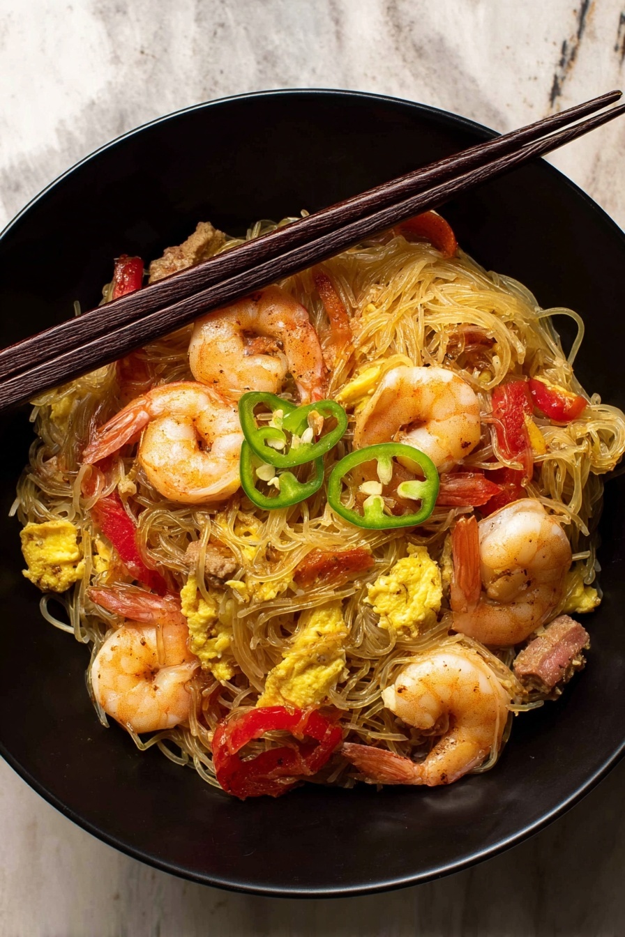 Singapore Noodles with Shrimp and Char Siu, Singapore Noodles, Shrimp and Char Siu Stir-fry, Asian noodle recipes, quick Asian dinner ideas - The image shows a black bowl filled with a noodle dish. The bottom layer is thin, light brown noodles loosely piled. On top, there are several whole cooked shrimp with a slightly pink and orange color. Mixed in are bright red strips of bell pepper and pieces of yellow scrambled egg. There are small chunks of brown meat scattered through the dish. Thin slices of green chili peppers are placed on the top, adding a fresh color contrast. A pair of dark brown chopsticks rest across the bowl on the top edge. The bowl is set on a surface with a white marbled texture. photo taken with an iphone --ar 2:3 --v 7