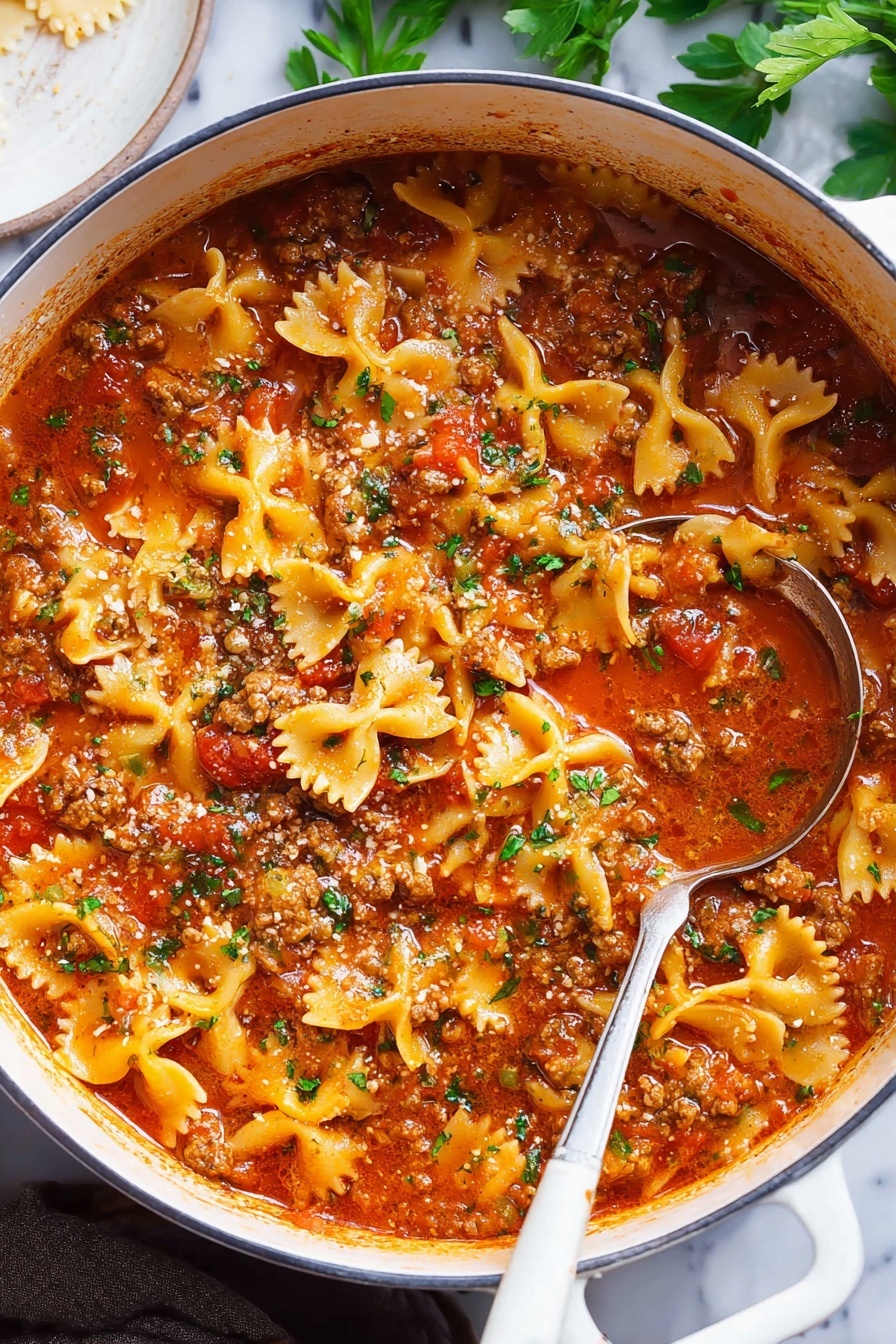 Lasagna Soup, easy lasagna soup recipe, hearty lasagna soup, cozy soup recipes, quick weeknight dinners - A large white pot filled with a thick stew made of bowtie pasta, ground meat, and rich red tomato sauce, garnished with small bits of green herbs on top; the sauce has a shiny, slightly oily surface with tomatoes and herbs visible throughout. A silver ladle with a white handle rests inside the pot, partially submerged in the stew. The background shows a white marbled surface with some green leaves and a white round dish partially visible on the side. photo taken with an iphone --ar 2:3 --v 7