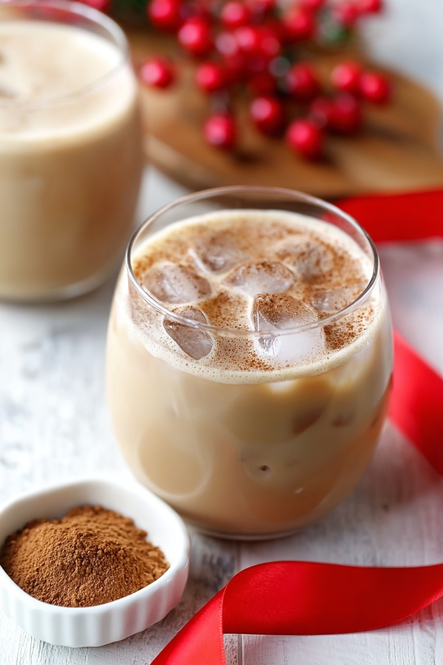 Eggnog White Russian Cocktail, holiday eggnog cocktail, festive White Russian, creamy holiday drinks, Christmas cocktail recipes - The image shows a clear glass filled with dark coffee at the bottom layer, with a woman's hand pouring white cream into it from above. The cream swirls into the coffee, creating a mix of light brown and creamy white patterns with a smooth texture. The glass sits on a wooden surface with a red ribbon nearby, and blurred bottles and red berries are in the background. photo taken with an iphone --ar 2:3 --v 7