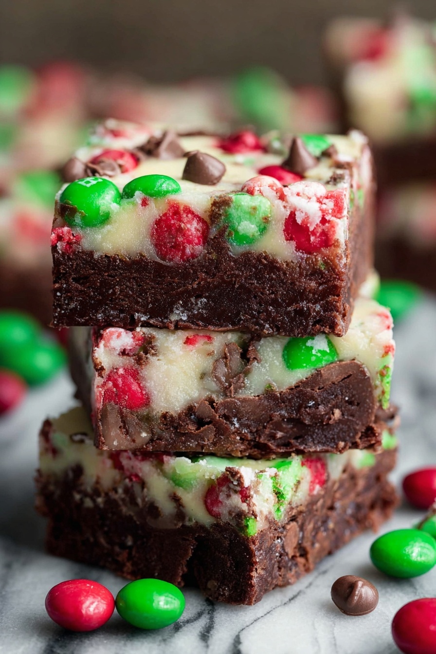 Christmas Layer Brownie Bars, festive brownie bars, holiday brownie dessert, layered brownie recipe, Christmas dessert ideas - The image shows a close-up of three stacked dessert bars with two clear layers. The bottom layer is thick, dense, and dark brown with a fudgy texture. The top layer is thinner and creamy white, embedded with red and green candy pieces and small chocolate chunks scattered throughout. Around the stack, several red and green round candies with a shiny shell are scattered. The background has a white marbled texture. photo taken with an iphone --ar 2:3 --v 7