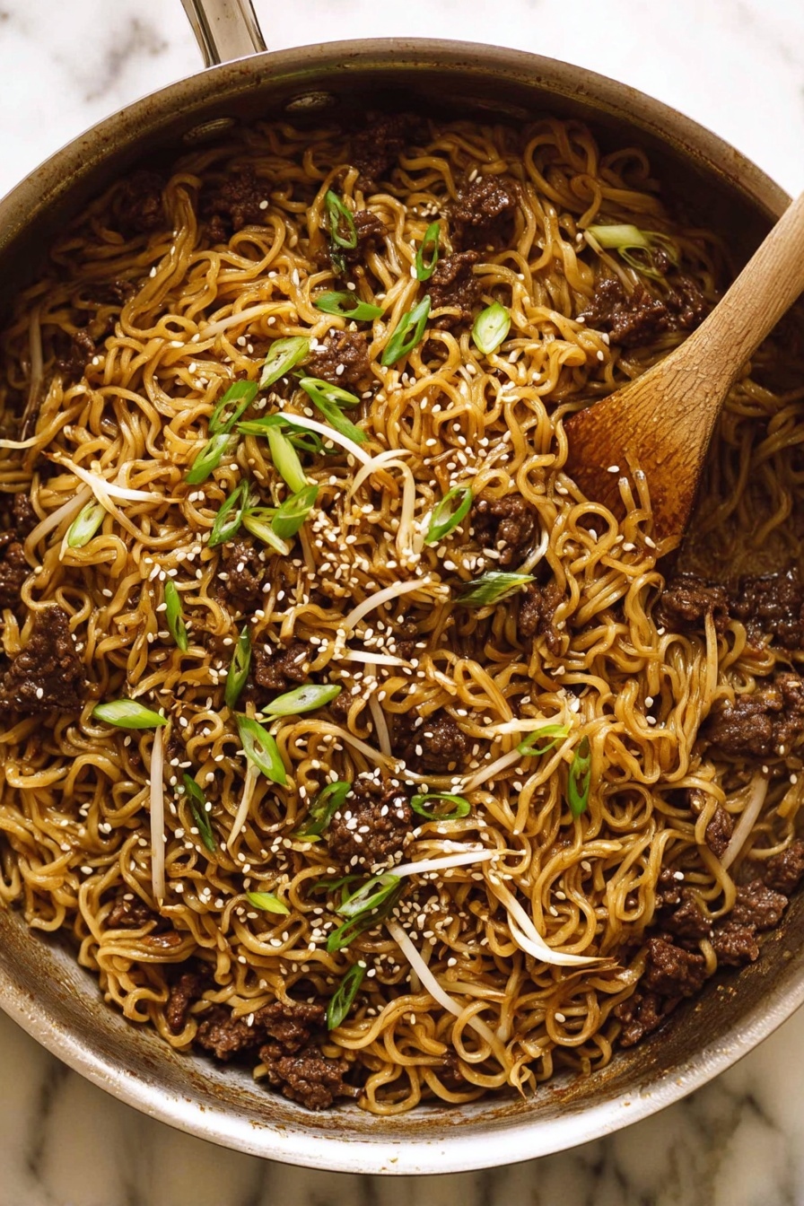 Quick Asian Beef Ramen, Asian Beef Ramen recipe, Fast ramen with beef, Easy Asian noodle bowl, Savory beef ramen - The image shows a metal pan filled with cooked noodles mixed with small pieces of dark brown meat and light bean sprouts. The noodles have a slightly shiny, brown color from the sauce. On top, there are sliced green onions and white sesame seeds scattered, adding texture and color contrast. A wooden spoon rests inside the pan, partially covered by the food. The pan sits on a white marbled surface. photo taken with an iphone --ar 2:3 --v 7