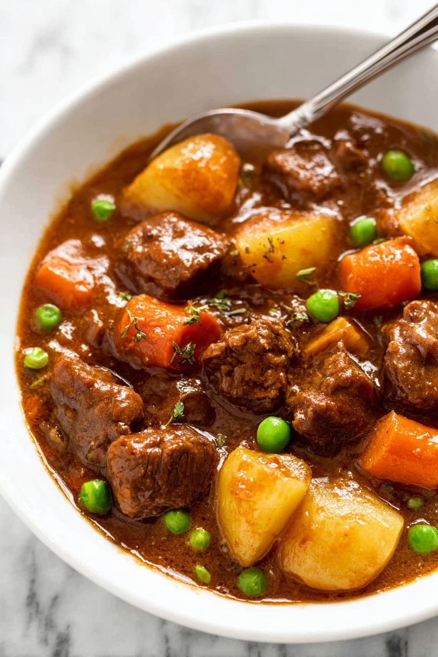 Slow Cooker Beef Stew with Red Wine, hearty beef stew, slow cooker beef recipes, red wine beef stew, comforting winter dinner - A white bowl filled with a stew showing three main layers: soft brown beef chunks covered in a shiny brown sauce, orange carrot pieces, and small green peas scattered around; small quartered light yellow potatoes are submerged in the thick sauce. A silver spoon rests in the bowl, partially visible at the top edge. The background shows a white marbled texture. photo taken with an iphone --ar 2:3 --v 7