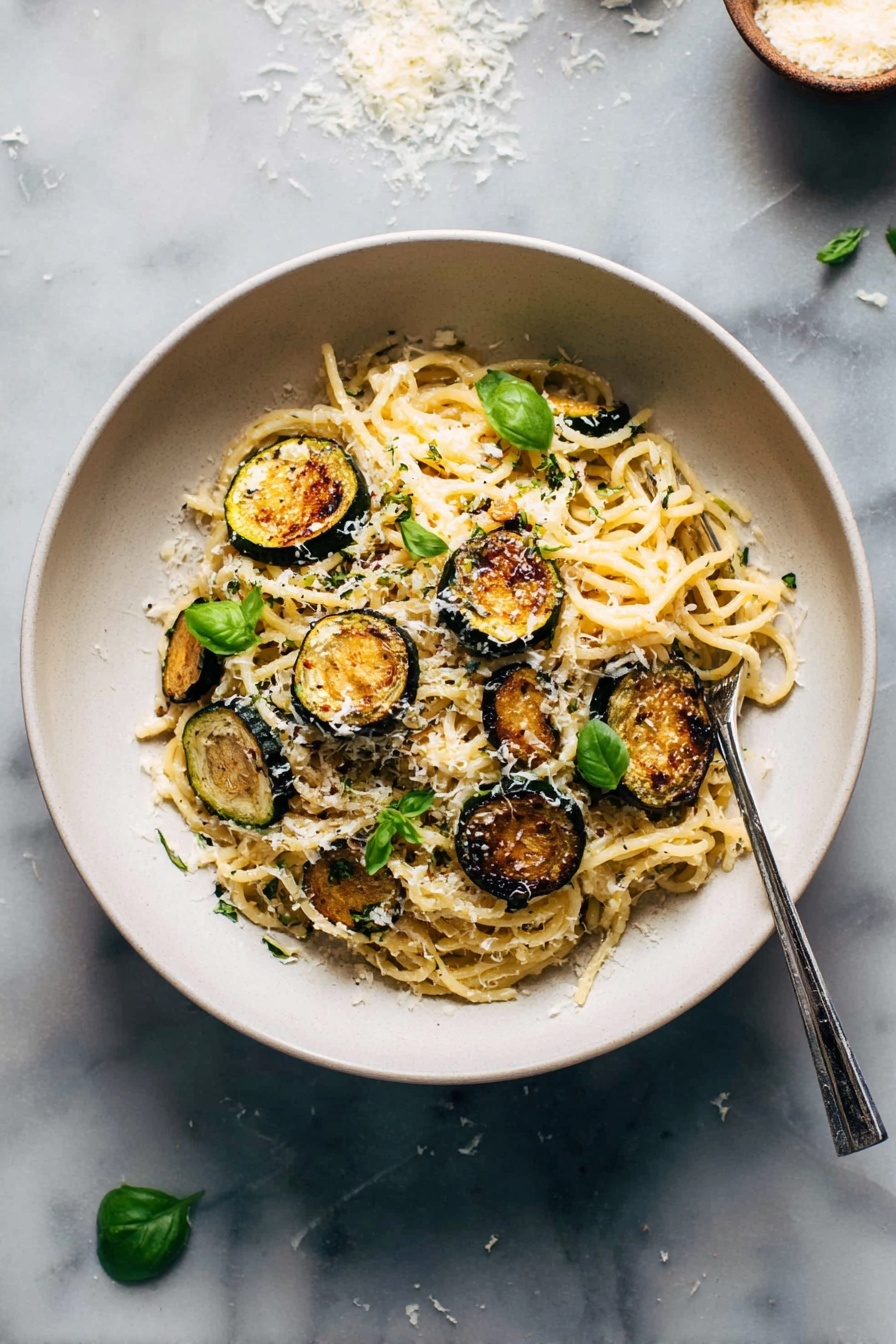 Creamy Zucchini Spaghetti, zucchini pasta with creamy sauce, Italian zucchini pasta, healthy zucchini pasta recipe, vegan zucchini spaghetti - A white bowl filled with a mound of spaghetti pasta at the center, topped with several golden-brown, round slices of roasted zucchini scattered on and around the noodles. Small bright green basil leaves are placed over the pasta, adding a fresh touch. The spaghetti is sprinkled with finely grated white cheese, giving a light dusting over the top. A silver fork rests on the right side inside the bowl. The bowl is set on a white marbled surface with some scattered grated cheese and a few basil leaves nearby. Photo taken with an iphone --ar 2:3 --v 7