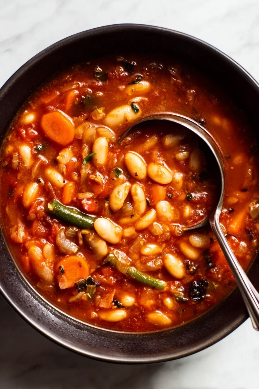 Hearty Minestrone Soup with Pasta, hearty minestrone soup, vegetable and pasta soup, healthy minestrone recipe, comforting tomato soup - A close-up view of a dark bowl filled with a thick soup that has many white beans, slices of orange carrots, and small pieces of green beans mixed in a rich, reddish-brown broth. The soup looks chunky with visible bits of vegetables and herbs throughout, giving it a hearty and comforting appearance. A shiny silver ladle with a long handle rests inside the bowl, partially submerged in the soup, with the handle leaning on the edge of the bowl. The bowl sits on a white marbled surface. Photo taken with an iphone --ar 2:3 --v 7