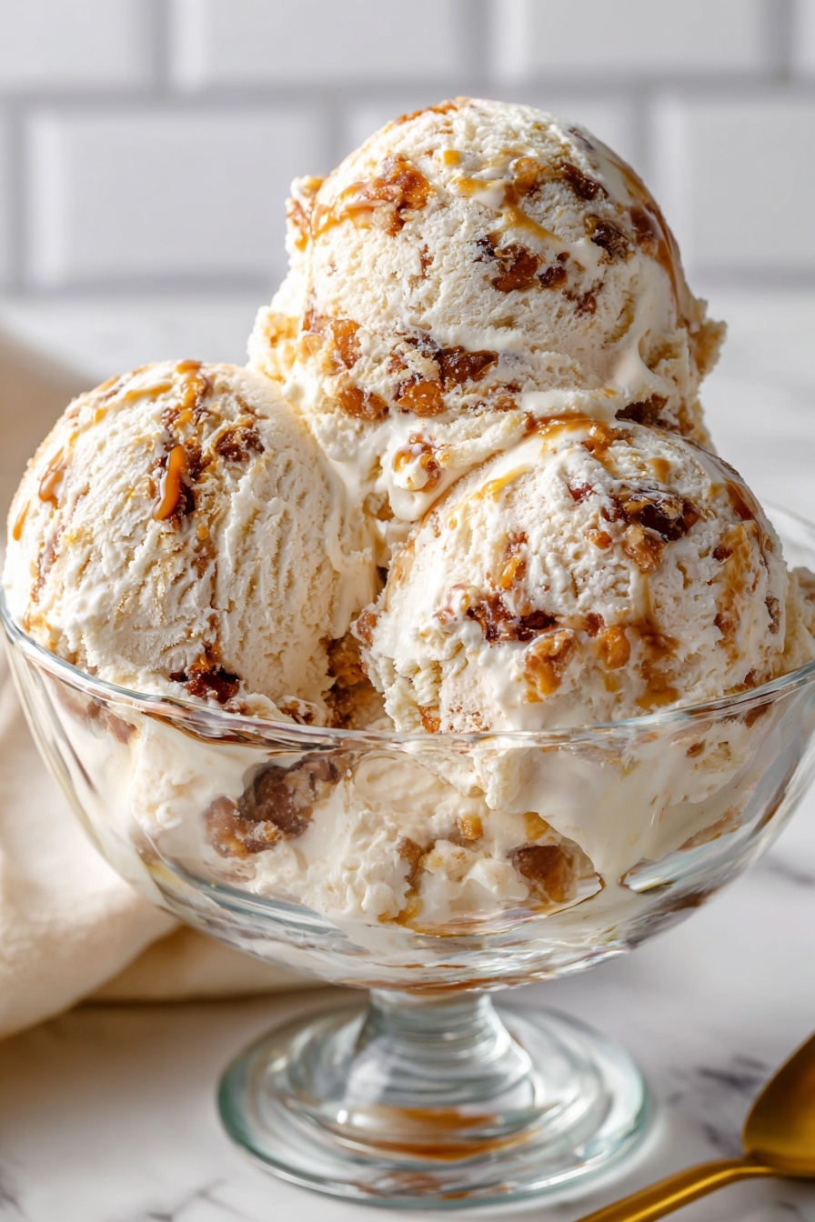 Salted Caramel Cottage Cheese Ice Cream, healthy ice cream alternatives, easy homemade ice cream, natural sweetened frozen dessert, creamy cottage cheese ice cream - The image shows three large scoops of creamy ice cream in a clear glass bowl. The ice cream is pale off-white with uneven swirls and chunks of dark caramel brown mixed throughout, giving it a textured look. The bowl sits on a white marbled surface, and behind it is a soft-focus white tile background. A gold spoon lies nearby on the surface. The overall look is smooth with some rough caramel bits, making the ice cream look rich and inviting. Photo taken with an iphone --ar 2:3 --v 7