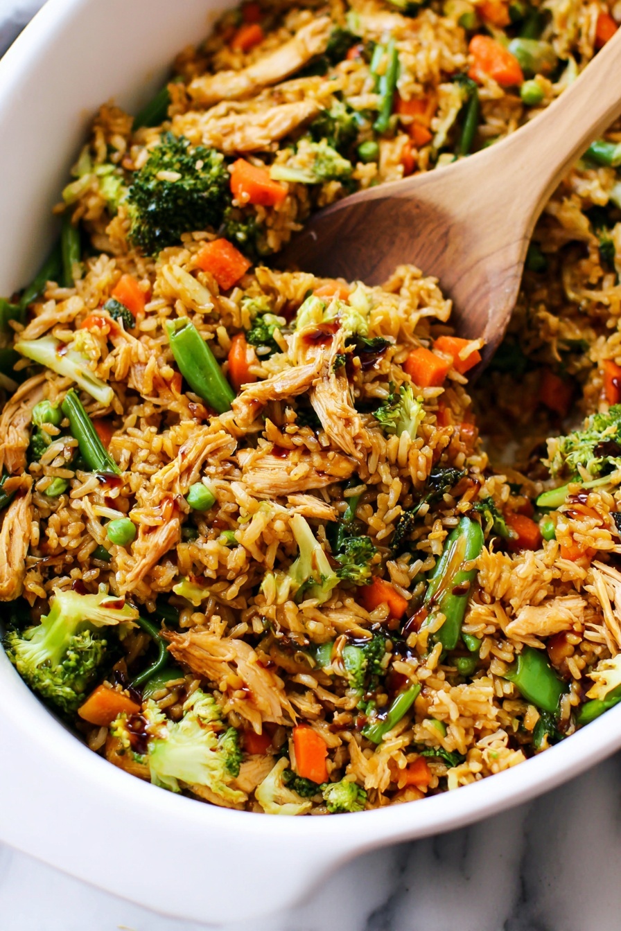 Teriyaki Chicken Casserole, easy chicken casserole, healthy chicken bake, weeknight dinner ideas, savory casserole recipes - The image shows a close-up of a white dish filled with a colorful fried rice mix. The dish has multiple layers: the base layer is golden-brown cooked rice, mixed with small pieces of shredded light brown cooked chicken. Scattered throughout are bright green broccoli florets and snap peas, as well as vibrant orange baby carrots. The vegetables add texture and color contrast, while some parts of the rice have a glossy look from a dark soy sauce drizzled on top. A wooden spatula is partially buried in the mixture, lifting some of the rice and vegetables. The dish is placed on a white marbled surface. Photo taken with an iphone --ar 2:3 --v 7