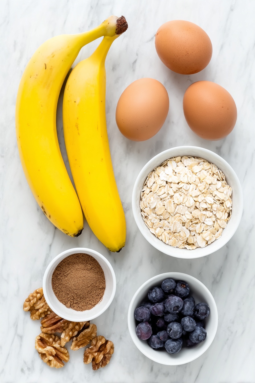 Healthy Banana Oat Pancakes, healthy breakfast recipes, easy banana pancakes, nutritious pancake ideas, quick wholesome breakfast - Flat lay of two ripe bananas with natural brown speckles, two whole uncracked brown eggs, a small white ceramic bowl filled with rolled oats, a small white bowl holding ground cinnamon powder, a few fresh blueberries scattered beside a small pile of walnut halves, all arranged symmetrically and balanced, placed on a clean white marble surface, soft natural light, photo taken with an iPhone, professional food photography style, fresh ingredients, white ceramic bowls, no bottles, no duplicates, no utensils, no packaging --ar 2:3 --v 7 --p m7354615311229779997